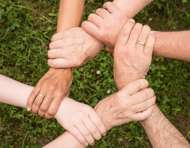 Photograph of six hands connecting - Community resilience - Resilience Forum